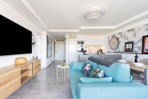 a living room with a blue couch and a kitchen at Apartment Royal Sunset Loggia in Palm-Mar