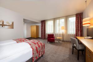 Cette chambre comprend un lit et un bureau. dans l'établissement Holiday Inn Frankfurt Airport - Neu-Isenburg, an IHG Hotel, à Neu-Isenburg
