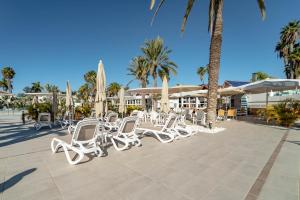 - un ensemble de chaises et de parasols blancs sur une terrasse dans l'établissement Hotel LIVVO Dunagolf Suites, à Maspalomas