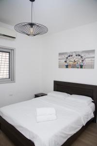 a bedroom with a white bed with a black headboard at Apartments4you Etsel in Bat Yam