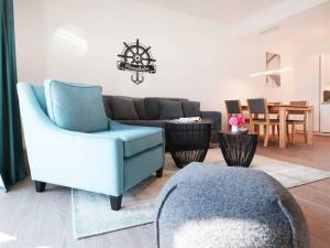 uma sala de estar com uma cadeira azul e um sofá em Hafenspitze App 05 em Wismar