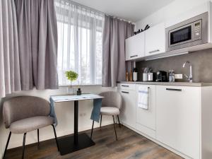 a kitchen with white cabinets and a table and chairs at limehome München in Munich