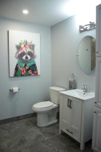 a bathroom with a toilet and a painting of a raccoon at CARLETON INN & COTTAGES in Bridgetown