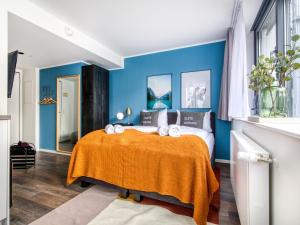 a bedroom with blue walls and a bed with a orange blanket at limehome München in Munich