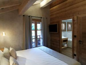 ein Schlafzimmer mit einem großen Bett und einem TV in der Unterkunft Chalet Jardin d'Angèle Chambres d'hôtes in Courchevel