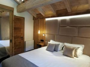 a bedroom with a large bed with white sheets and pillows at Chalet Jardin d'Angèle Chambres d'hôtes in Courchevel