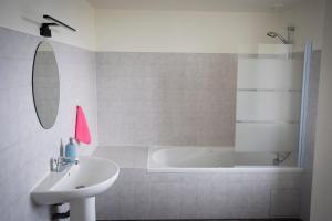 ein weißes Badezimmer mit einem Waschbecken und einer Badewanne in der Unterkunft Appartement de 60m2 à 2 pas du port de Paimpol in Paimpol