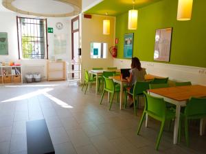 a woman sitting at a table in a room with green walls at Ostello S. Fosca - CPU Venice Hostels in Venice