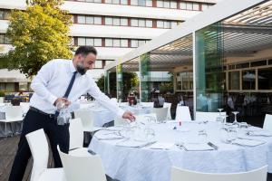 a man standing in front of a table with glasses at Living Place Hotel in Villanova