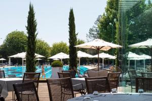 a restaurant with tables and umbrellas next to a pool at Living Place Hotel in Villanova