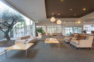 a living room with couches and tables and windows at Living Place Hotel in Villanova