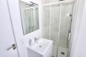 ein weißes Bad mit einem Waschbecken und einer Dusche in der Unterkunft Napoléon Gare 5 STUDIO 1er Etage ByLocly in Pontivy