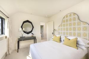 a white bedroom with a large white bed with yellow pillows at Decoy Farm House in Somerton