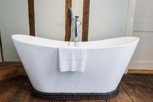 una vasca da bagno bianca con un asciugamano di The Boarding House a Halesworth