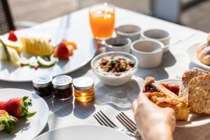 a table with plates of food and a person holding a piece of bread at Living Place Hotel in Villanova