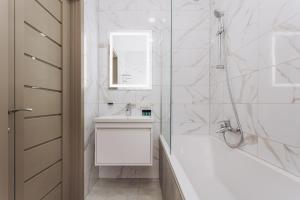 a white bathroom with a tub and a sink at Apart Lux Elegant in Sumy