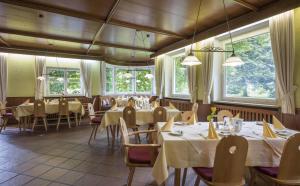 a dining room with tables and chairs and windows at Haus Auerbach in Oberaudorf