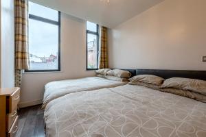 a bedroom with two beds and two windows at Lever St Central in Manchester