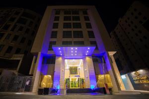 budynek z niebieskimi światłami przed nim w obiekcie مبيت التحلية للأجنحة الفندقية w mieście Dżudda