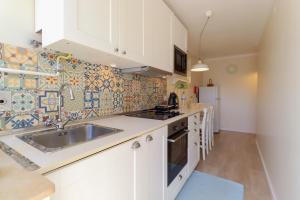 a kitchen with white cabinets and a sink at Casa da Nespereira - City Centre Duplex Apt with Balcony in Viana do Castelo