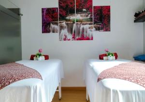 2 Betten in einem Zimmer mit Wasserfall-Gemälde an der Wand in der Unterkunft Hotel Internacional La Triada in Bucaramanga