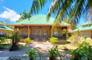 une maison jaune avec un toit vert dans l'établissement Hostellerie La Digue, à La Digue