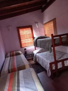 a room with three bunk beds and two windows at Lo de Ely in Tafí del Valle
