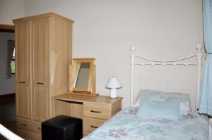 a bedroom with a bed and a dresser with a mirror at Blaengader Cottages DINAS in Aberystwyth