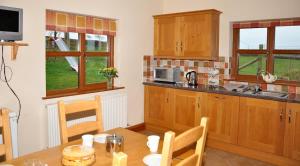 cocina con mesa, microondas, mesa y sillas en Blaengader Cottages DINAS en Aberystwyth