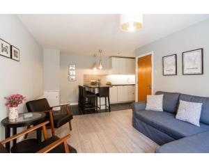 ein Wohnzimmer mit einer blauen Couch und einer Küche in der Unterkunft Central Belfast Apartments Alfred Street in Belfast