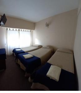 a small room with three beds and a window at Hotel PerlaMar in Mar del Plata