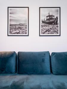 Un sofá azul con dos cuadros en la pared en Apartament z widokiem, 10min od morza en Gdansk