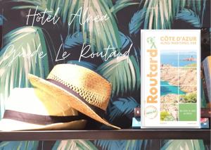 Un chapeau assis sur une étagère à côté d'un livre dans l'établissement Hotel Alnea, à Cannes