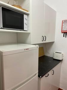 a kitchen with white cabinets and a microwave at T0 Pedras D'el Rei in Tavira