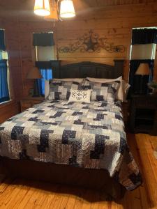 a bedroom with a bed with a black and white quilt at Lake Whitney Log Cabin in Lakewood Harbor