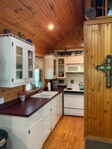 Lake Whitney Log Cabin في Lakewood Harbor: مطبخ بدولاب بيضاء وسقف خشبي