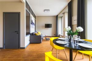 una sala da pranzo con tavolo e sedie gialle di Grani Aparthotel a San Pietroburgo