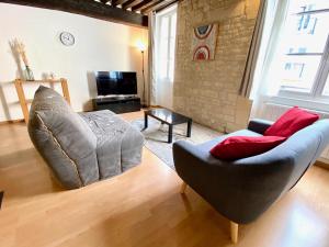 uma sala de estar com um sofá e uma cadeira em Nashira YourHostHelper em Caen