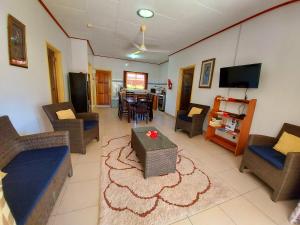 ein Wohnzimmer mit Sofas und Stühlen sowie einem TV in der Unterkunft Hostellerie La Digue in La Digue