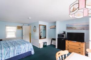 - une chambre avec un lit, une télévision et un bureau dans l'établissement A Beach Breeze Inn, à West Harwich