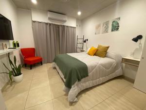 1 dormitorio con 1 cama y 1 silla roja en Studio Estrada 2 Escobar en Belén de Escobar