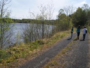 três pessoas a caminhar por uma estrada de terra ao lado de um rio em Clancys Of Glenfarne em Glenfarne