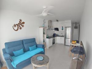 un soggiorno con divano blu e una cucina di Apartment Namaste- Amazing sea view & infinity pool - good Wifi - smart tv-Residence Senator a Costa Teguise