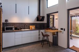 uma cozinha com armários brancos, uma mesa e um banco em Papaya Lances Studios em Tarifa