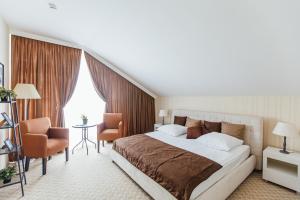 una habitación de hotel con una cama grande y una silla en Dolphin Planet Hotel & SPA, en Yaroslavl