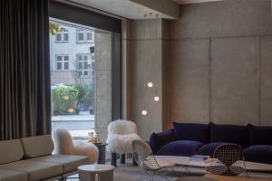 ein Wohnzimmer mit einem Sofa, Stühlen und einem Fenster in der Unterkunft EmiLu Design Hotel in Stuttgart