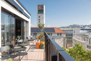 a balcony with chairs and a clock tower in the background at EmiLu Design Hotel in Stuttgart