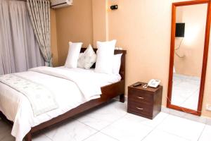 um quarto com uma cama, um espelho e um telefone em Residence Le Bonheur - Serviced apartment by Douala Airport/Mall em Douala