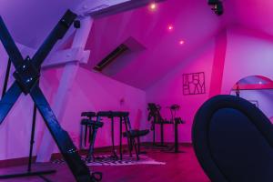 Zimmer mit rosafarbenen Lichtern und Hockern in der Unterkunft La Villa Monroe - Un écrin de volupté épicée in Le Vézier