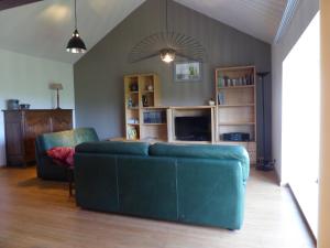 sala de estar con sofá azul y TV en La Vannerie en Havelange